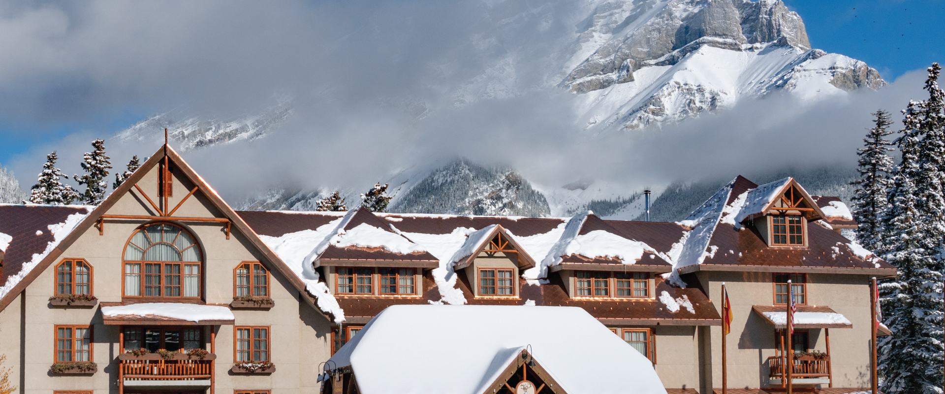 banff mountian view lodge in winter with snowy roofs and mountain peaks behind